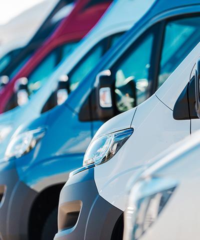 Momento Renovar flota de vehiculos - Flota de furgonetas de empresa de diferentes colores aparcadas unas junto a otras