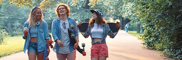 Cuenta y Libreta Joven Up - Grupo de jóvenes vestidos con ropa moderna con patinetes, sonriendo junto a un parque rodeado de arboles