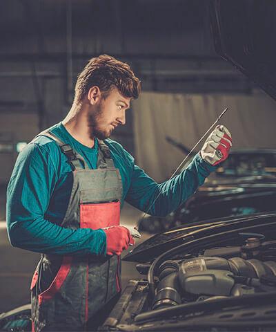 Ventajas de  Seguro Multirriesgo Industrial - Mecanico revisando el nivel de aceite de una furgoneta en un taller de coches